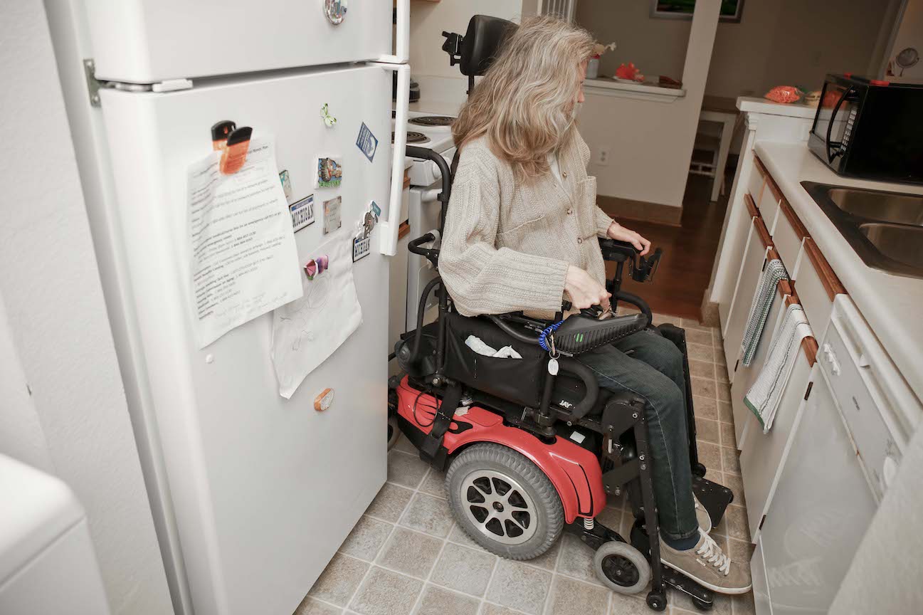 Woman using wheelchair turning around in narrow kitchen