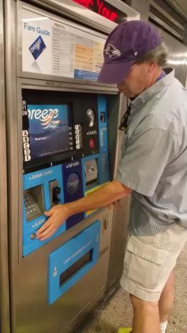 Man touches braille on kiosk for public transportation system (MARTA)