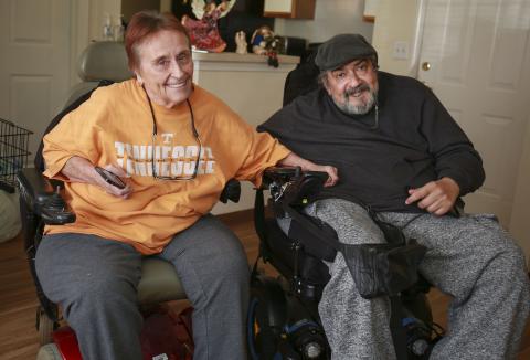 man and woman in wheelchairs holding hands and smiling
