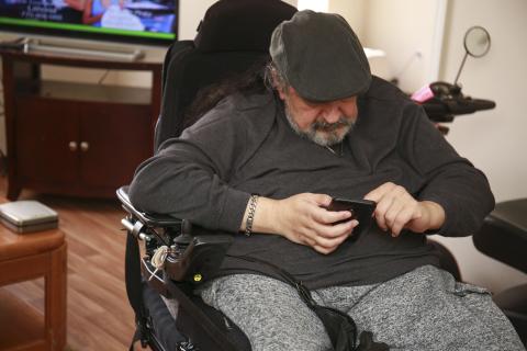 man sitting on wheelchair using smart phone